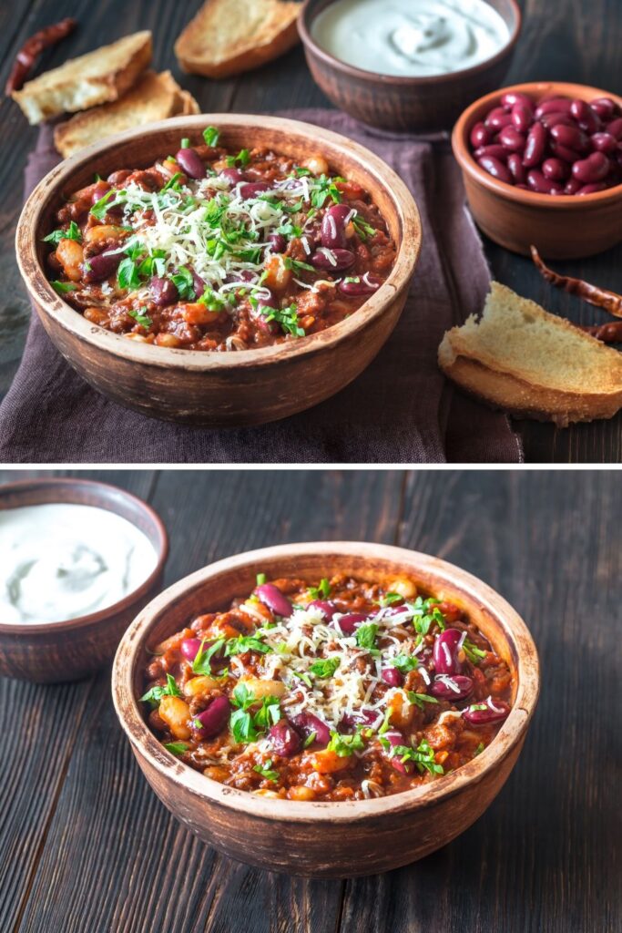 Two bowls of Ina Garten's turkey chili presented on a wooden surface, one topped with shredded cheese and herbs, with sides of sour cream and crusty bread.